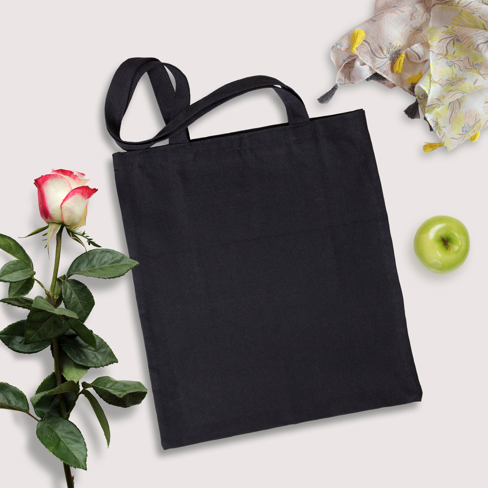 Black blank cotton eco tote bag with a rose, scarf and green apple, top view styled design mockup